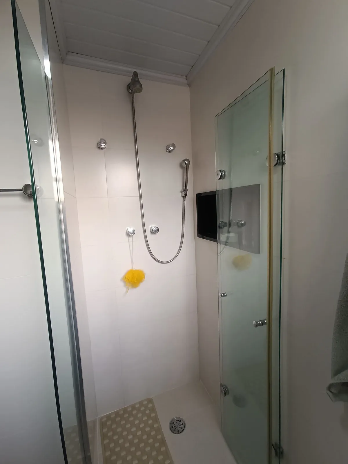 Box de banheiro com duas duchas, azulejo branco e portas de vidro, antes da reforma
