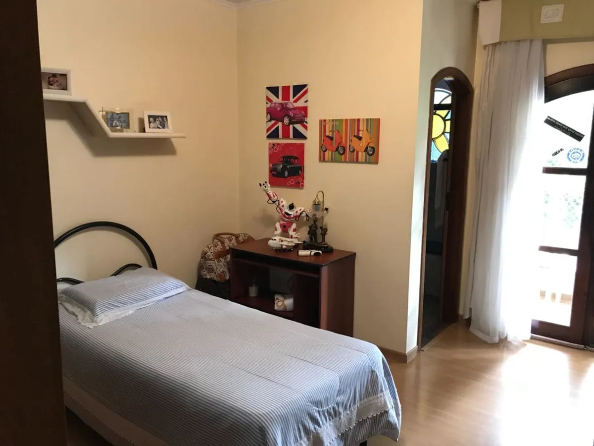 Quarto de solteiro com cama de colcha listrada, escrivaninha de madeira e quadros pop art na parede, antes da reforma