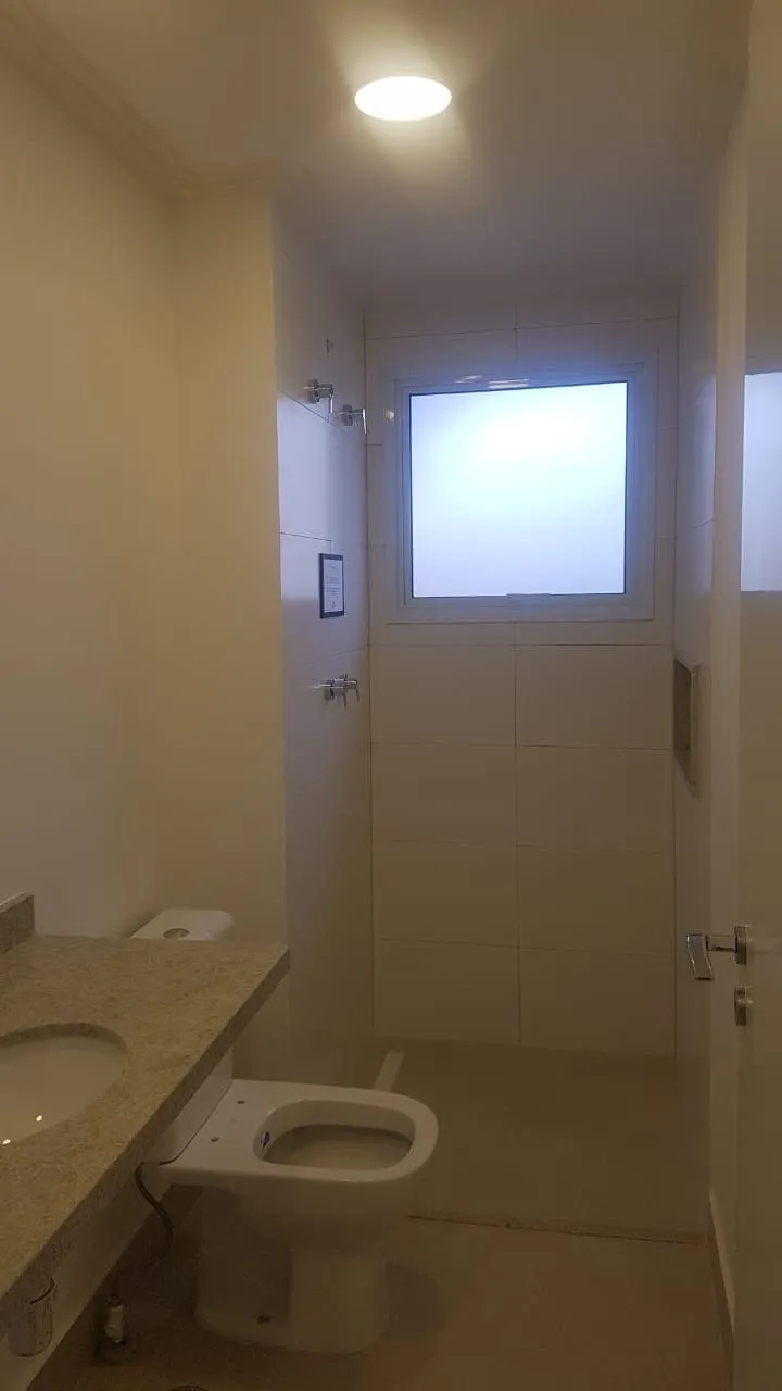 Banheiro com bancada de granito, vaso sanitário e box com janela, revestimento branco, antes da reforma