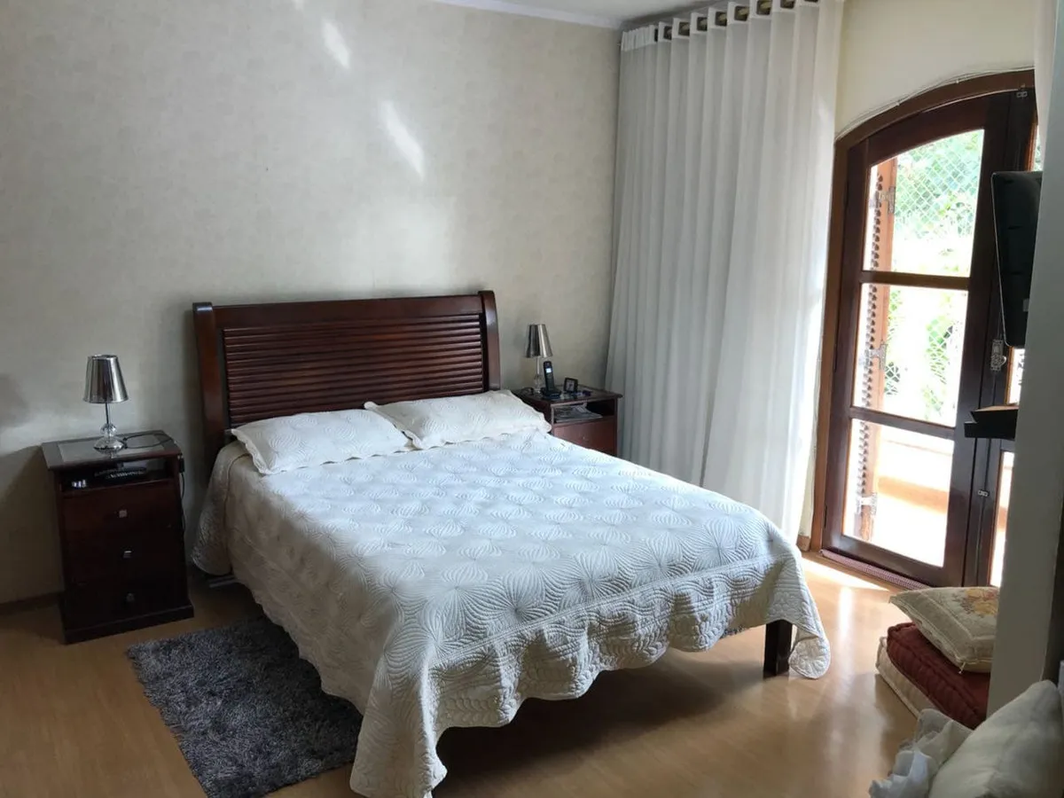 Suíte com cama de casal, cabeceira de madeira, criados-mudos e porta francesa de madeira para a sacada, antes da reforma