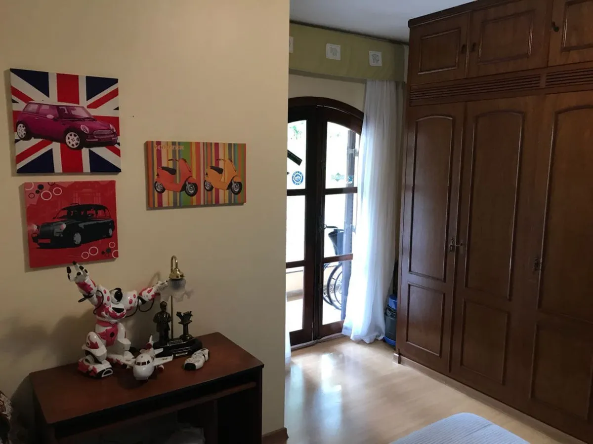Quarto infantil com quadros pop art, guarda-roupa de madeira escura e porta francesa para a sacada, antes da reforma