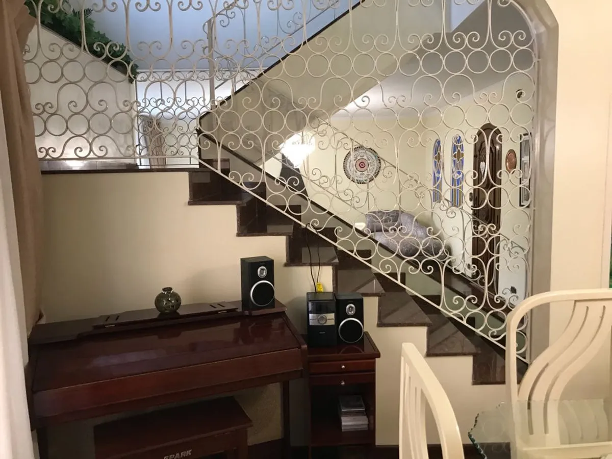 Escada de granito com guarda-corpo de ferro trabalhado branco e piano antigo embaixo, antes da reforma