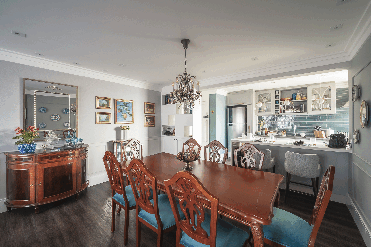 Sala de jantar integrada à cozinha, com aparador de madeira, lustre de cristal e parede de pratos azuis