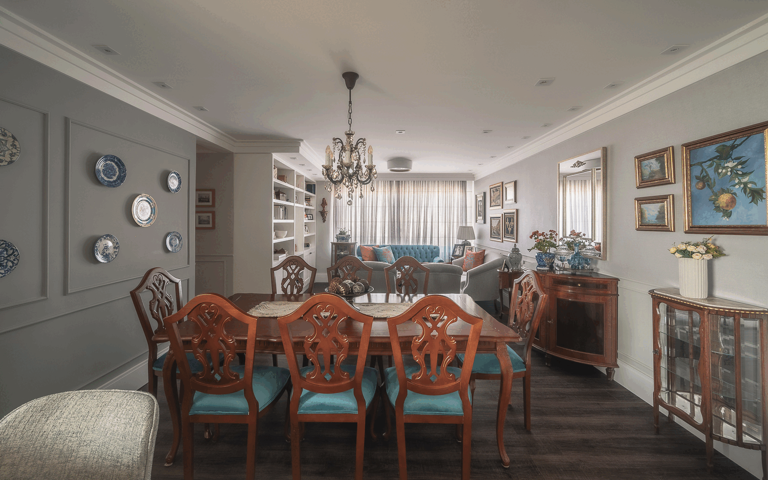 Sala de estar e jantar integradas, com sofá azul, cadeiras de madeira e parede cinza de pratos decorativos