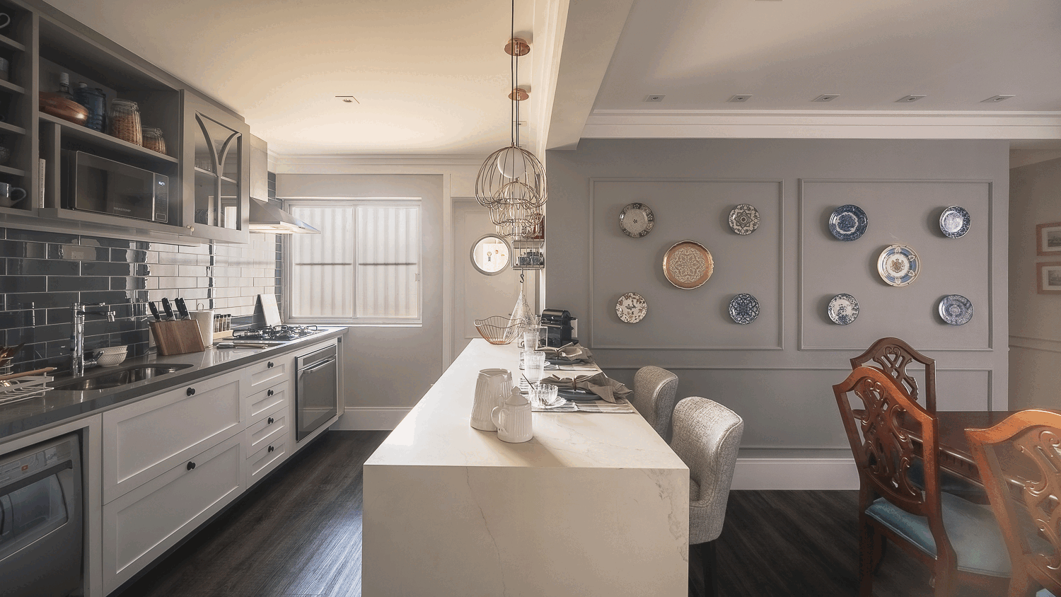 Cozinha cinza clássica com geladeira inox, backsplash de metrô azul e ilha branca com pendentes de gaiola dourados